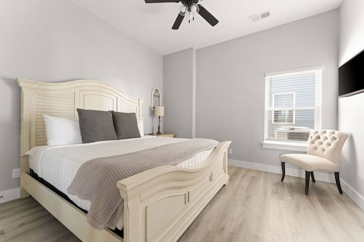 - Смирувачките сиви ѕидови и рамката на креветот со кремасти тонови создаваат мирна атмосфера
- Природната светлина го исполнува просторот низ големиот прозорец покрај стол со туф
- Едноставниот, чист дизајн прави оваа соба да изгледа свежо, проветрено и ненатрупано