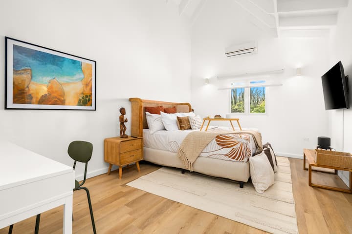 Habitación luminosa con una hermosa cama tamaño queen, almohadas y mantas adicionales, vestidor, aire acondicionado, televisor inteligente, espacio de trabajo dedicado con escritorio y silla, conexión Wi-Fi de alta velocidad en todo el alojamiento con conexión Ethernet opcional y baño moderno privado.