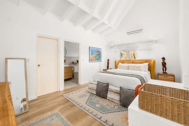 Amplio y luminoso segundo dormitorio con cama tamaño queen, aire acondicionado, baño privado moderno en suite, televisor inteligente, vestidor con almohadas y sábanas adicionales, armario para guardar ropa y escritorio con silla y conexión Ethernet.