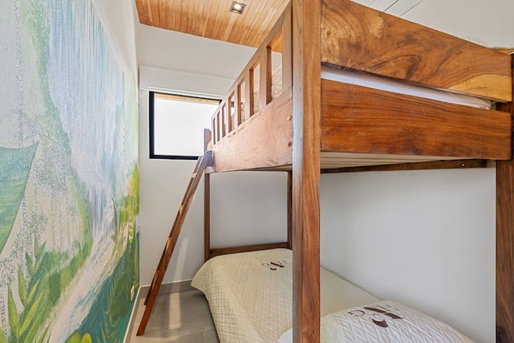 - Watoto na wageni sawa watapenda chumba hiki cha ghorofa chenye vitanda mahususi vya mbao
- Ukuta wa ukuta wa msituni unaongeza haiba ya kuchezea na jasura kwenye sehemu hiyo
- Mwangaza wa asili na umaliziaji rahisi huunda kona tulivu na yenye furaha ili kupumzika