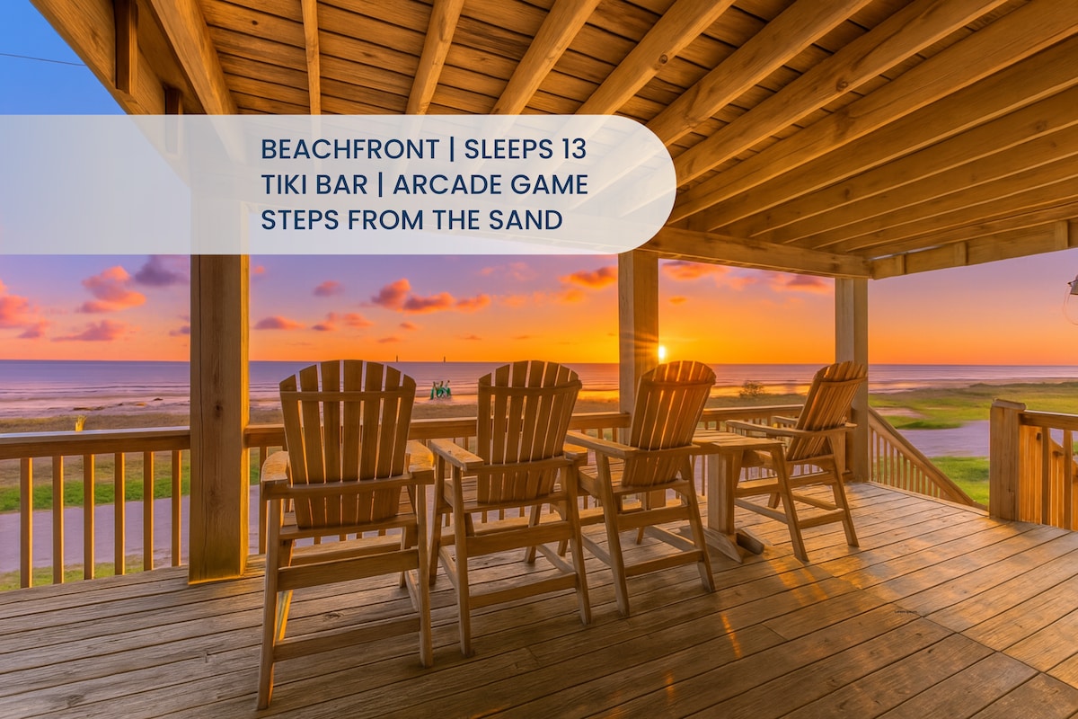 A spacious deck features wooden Adirondack chairs positioned to face stunning ocean views at sunset. The warm colors of the sky are reflected on the water, enhancing the serene atmosphere. The deck offers ample space for relaxation, making it an inviting outdoor area.
