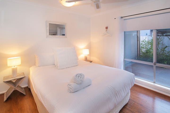Las texturas suaves y la iluminación suave crean un ambiente relajante en el segundo dormitorio, que se completa con una cama tamaño queen y una vista tranquila a la terraza trasera privada.