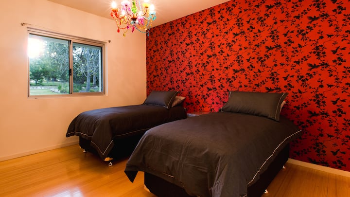 Ova dvokrevetna soba s odvojenim krevetima odiše energijom zahvaljujući upečatljivim tapetama, prirodnom svjetlu i pogledima na travnjak koji se proteže iza kuće.