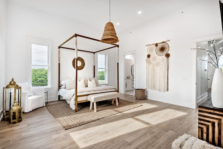 ห้องนอนที่เงียบสงบและกว้างขวางมีเตียงสี่เสาที่อบอุ่นพื้นผิวธรรมชาติและโทนสีเอิร์ธโทนที่นุ่มนวล