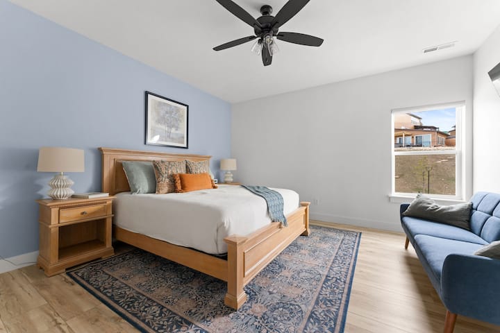 - Ponorte sa do plyšovej postele veľkosti King s bohatými textúrami a teplými zemitými tónmi.
- Elegantná stena s modrým zvýraznením a klasickým dreveným nábytkom dodávajú útulný charakter.
- Okno v okolí prepúšťa dostatok prirodzeného svetla a otvára relaxačný priestor.