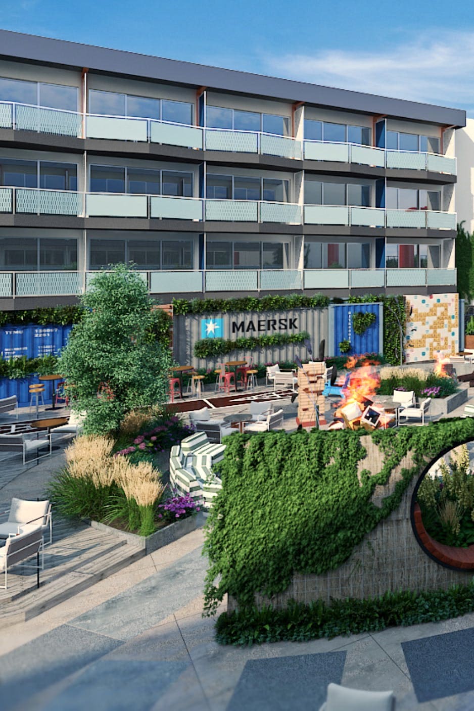 The hotel’s vibrant courtyard showcases a mix of shipping container lounges surrounded by greenery and fire pits. Stylish outdoor seating is arranged for social gatherings, while the colorful exterior of the building adds to the playful atmosphere. A clear sky complements the lively setting.