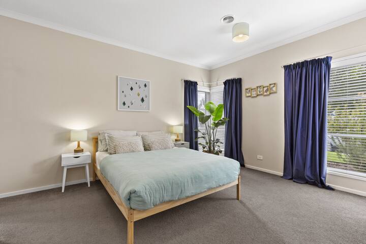 Lichte slaapkamer met comfortabel bed, grote ramen en knusse inrichting