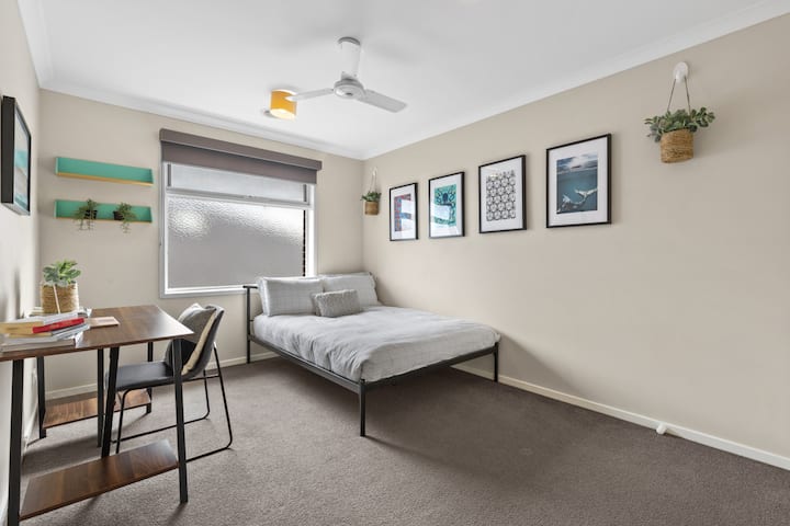 Veelzijdige slaapkamer met werkplek, comfortabel bed en daglicht
