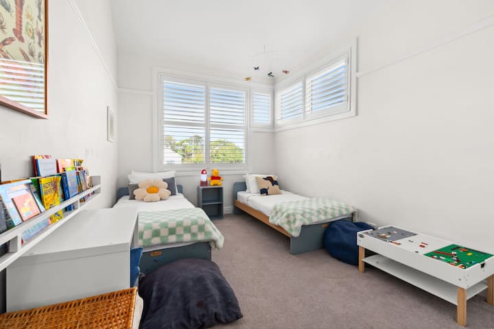 תנו לילדים לחלום ולשחק בחדר השינה השלישי, חדר זוגי עליז מלא בספרים, צעצועים, שולחן לגו ושתי מיטות יחיד.