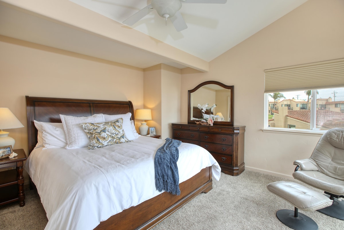 El baño principal cuenta con una cama tamaño king con cómoda ropa de cama blanca, TV y vistas al mar.