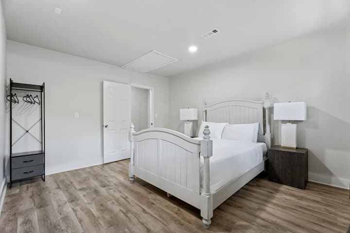 Rilassati in questa tranquilla camera da letto con un rustico telaio bianco del letto, un'illuminazione accogliente e un ampio spazio per rilassarsi dopo una lunga giornata.