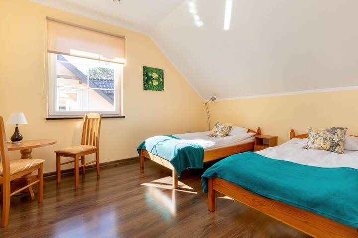 Спалня с две удобни единични легла, маса със столове и гардероб.