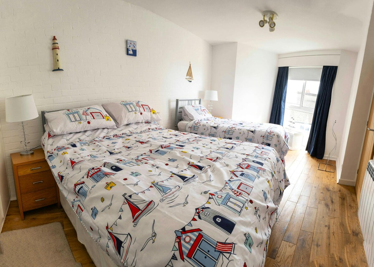 Slaapkamer met tweepersoonsbed en eenpersoonsbed, nachtkastjes en leeslampjes, raam