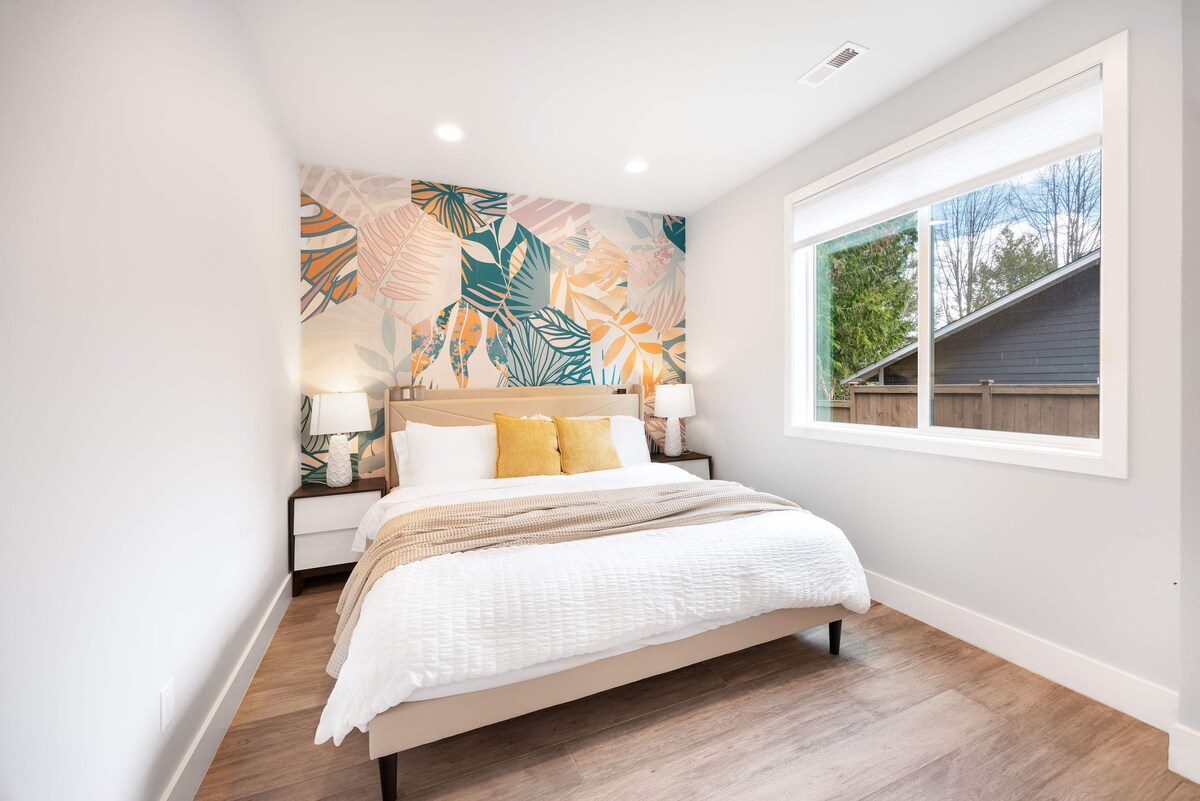 Una cama tamaño queen con una elegante pared de cabecera con patrón de hojas crea un refugio natural y acogedor.