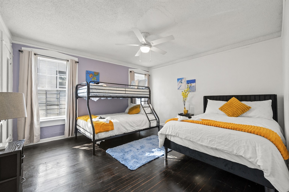 Habitación con literas con dos camas tamaño completo, una cama doble, un televisor inteligente y un espejo de cuerpo entero.