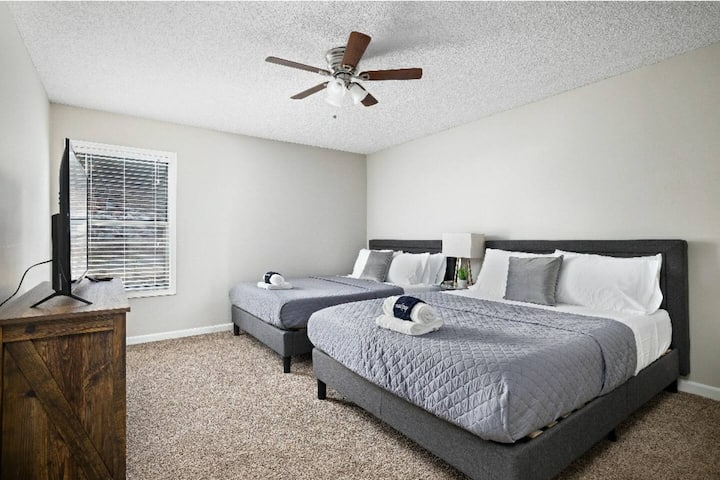 Ďalší pohľad na veľkú spálňu s dvoma manželskými posteľami, komodou a televízorom s plochou obrazovkou.