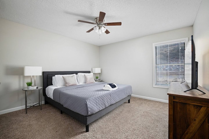 Útulná spálňa s luxusnou manželskou posteľou King, nočnými stolíkmi a prirodzeným svetlom z veľkých okien.