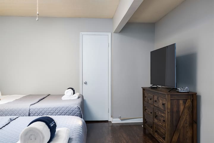 Relaxačná spálňa s dvoma manželskými posteľami, inteligentnou televíziou a minimalistickou výzdobou