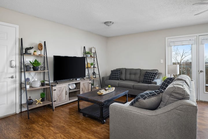 Priestranná obývacia izba s útulnou sivou sekciou, inteligentným televízorom a štýlovou výzdobou, ideálna na oddych.