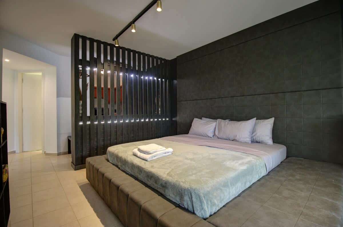 Vlastná manželská posteľ King s modernou skriňou, ktorá oddeľuje hlavnú spálňu od kuchynského kúta. Moderné osvetlenie dráhy a luster. 