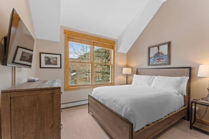 Სტუმრების საძინებელი, რომელშიც დგას ორადგილიანი საწოლი და დამონტაჟებული ტელევიზორი. 