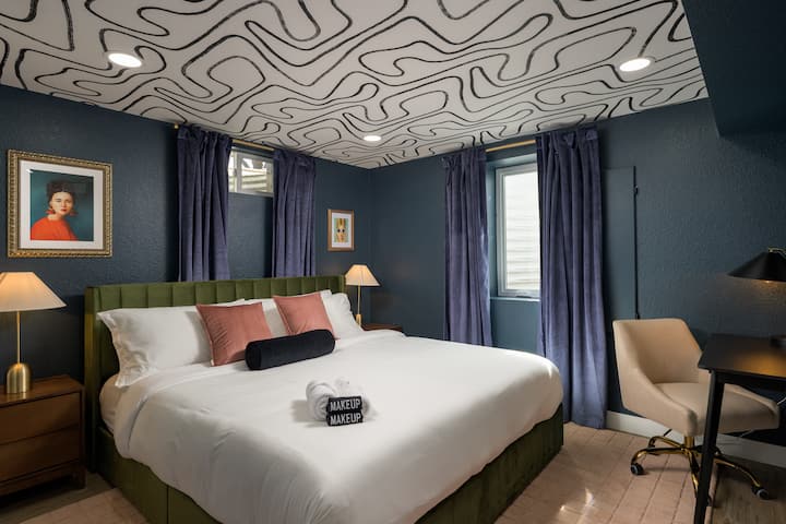 Moderna spavaća soba s umjetničkim detaljima na stropu, raskošnim zavjesama i funkcionalnim radnim stolom za rad ili pisanje dnevnika.