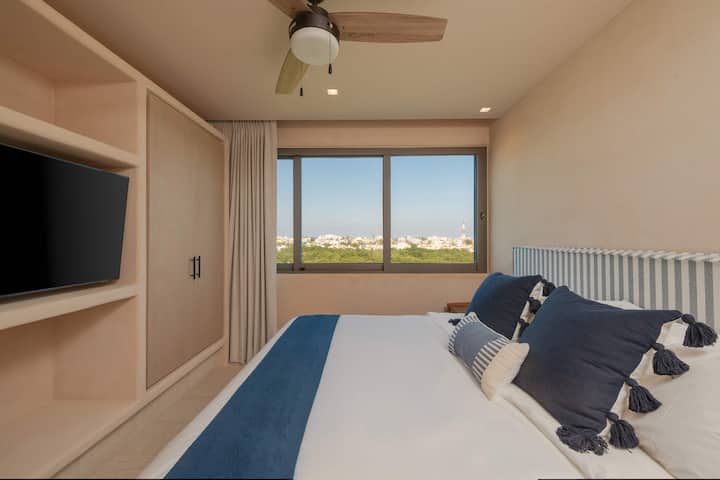 Соба со двоен кревет, телевизор, клима уред и тавански вентилатор. Поглед кон морето. 