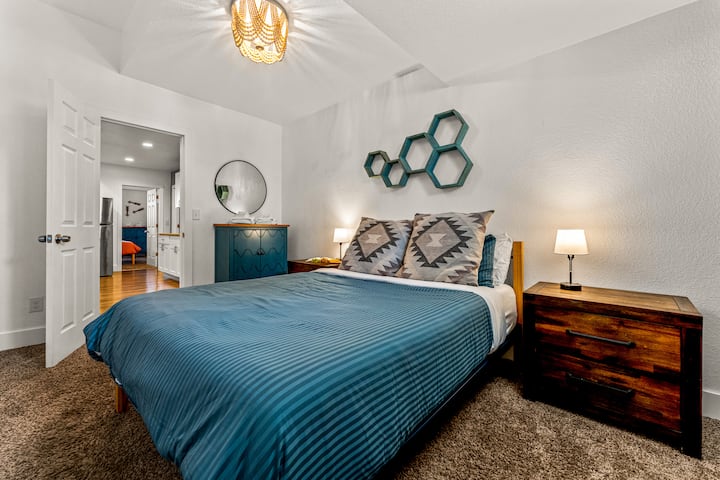 - Брачен кревет (широк 150-179 см) со задебелени перници и постелнина со пруги наспроти чисти бели ѕидови
- Уникатната шестоаголна ѕидна уметност додава разигран, модерен дизајнерски елемент
- Мекото осветлување, удобните текстури и отворениот распоред овозможуваат мирна ноќ