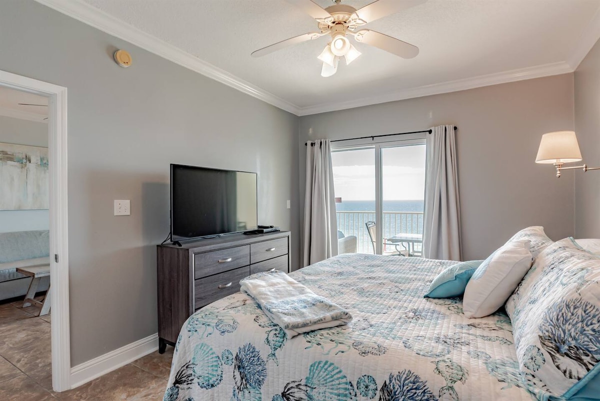 ห้องนอนใหญ่มีประตูกระจกบานเลื่อนพร้อมระเบียงพร้อมวิวทะเลริมชายหาด ห้องนอนนี้ตกแต่งด้วยเตียงคิงไซส์โต๊ะข้างเตียงตู้เสื้อผ้าทีวีขนาดใหญ่ตู้เสื้อผ้าและห้องน้ำเต็มรูปแบบในตัว