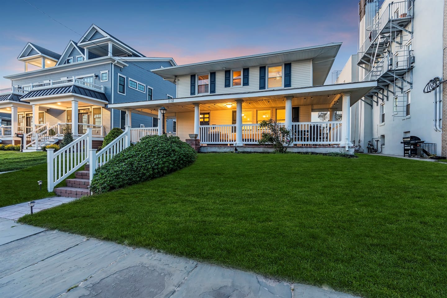 Unwind on the expansive front porch of this charming coastal-style retreat, just steps from the heart of town and perfect for relaxed evenings under the glow of warm porch lights.