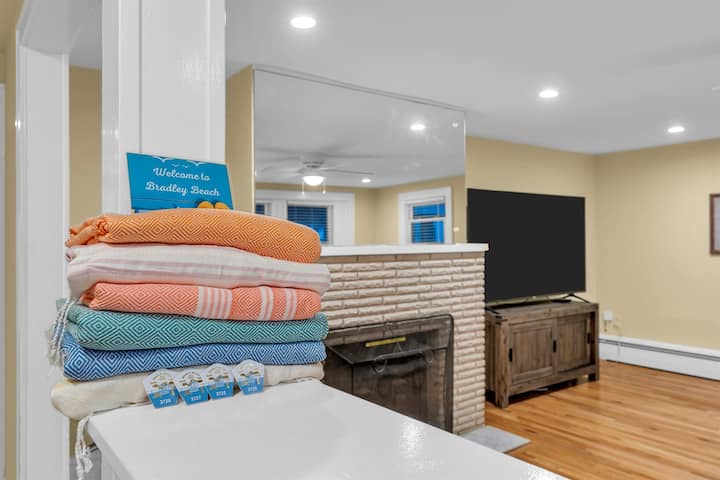 Four Bradley Beach seasonal beach badges with towels, chairs and an umbrella laid out for the beach