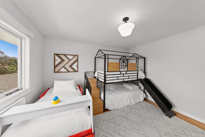 Una habitación diseñada para divertirse en una litera con tobogán y una cómoda cama individual para los dulces sueños y el tiempo de juego.