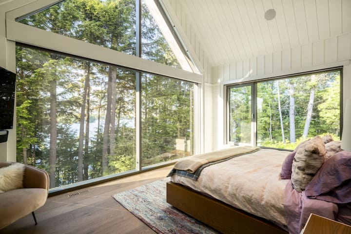 غرفة نوم رئيسية مع إضاءة طبيعية وإطلالات تشبه بيت الشجرة