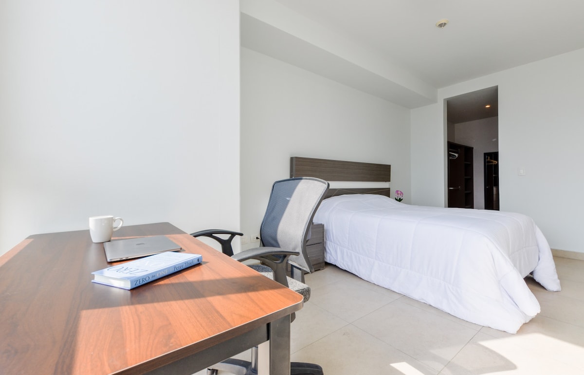 Gastenverblijf met bed, bureau en stoel.