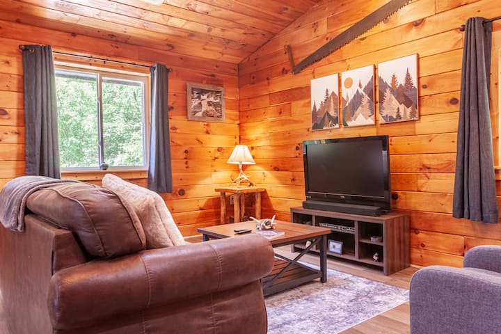 Ugodan dnevni boravak u planinskoj kući Edgeview s televizorom, prostorom za sjedenje i interijerom od toplog drveta.