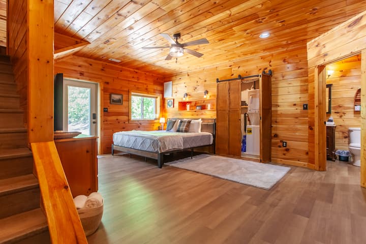 Spavaća soba u planinskoj kući Edgeview u Bryson Cityju s ravnim TV-om i zidovima obloženim drvom.