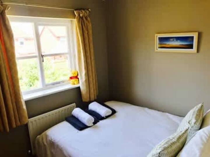 Segundo dormitorio con televisor inteligente montado en la pared.