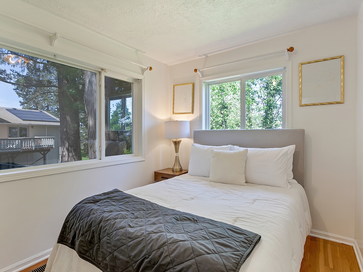 Bedroom 4 with king bed, TV, and large windows overlooking the backyard