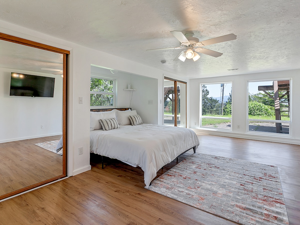 Primary bedroom with king bed and floor-to-ceiling windows showcasing the outdoors