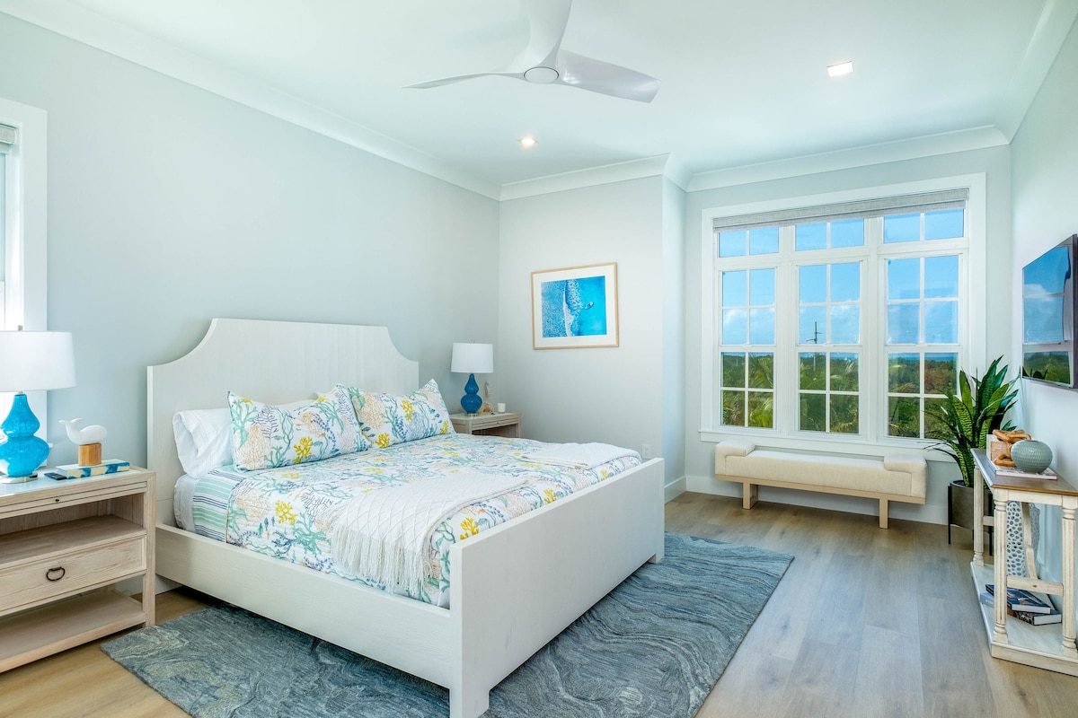Bright king bedroom in a luxury oceanfront Marathon Middle Keys villa with coastal décor, large window views and smart TV. Stylish Florida Keys lodging in SeaGlass Cove near marinas, beaches and waterfront dining, ideal for family travel.