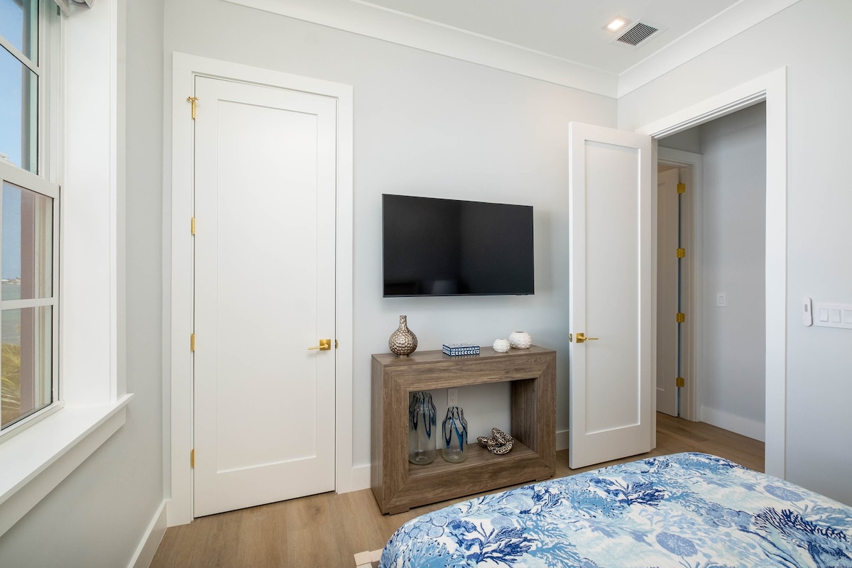 Cozy guest bedroom in a luxury Marathon Middle Keys villa with smart TV, coastal décor and light finishes. Florida Keys lodging in SeaGlass Cove near the Turtle Hospital, dolphin encounters and scenic Seven Mile Bridge views.