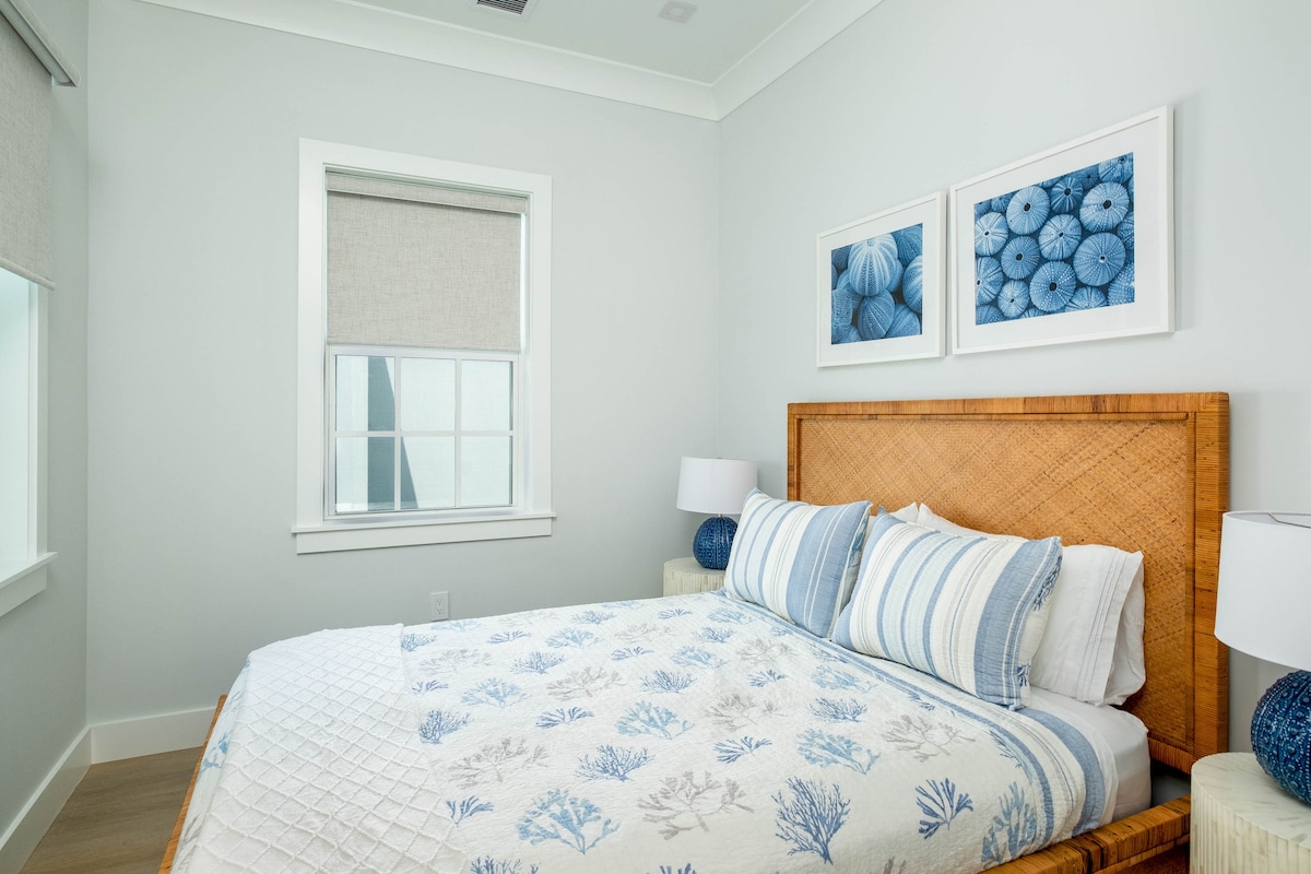Peaceful guest bedroom in a luxury Marathon Middle Keys villa with coastal décor, woven headboard and soft blue tones. Florida Keys lodging in SeaGlass Cove near Bahia Honda State Park, the Turtle Hospital and dolphin research experiences.