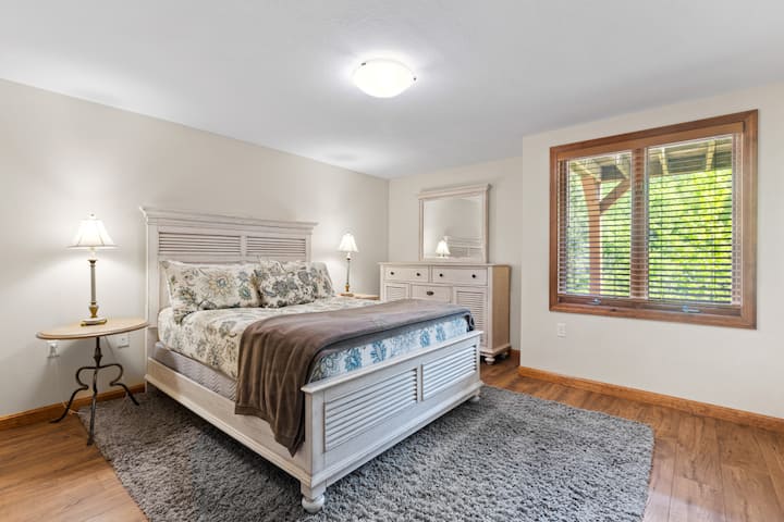 غرفة نوم مشرقة وجذابة بسرير بحجم متوسط وديكور ساحر على طراز الكوخ. حمام كامل يقع خارج الباب مباشرة