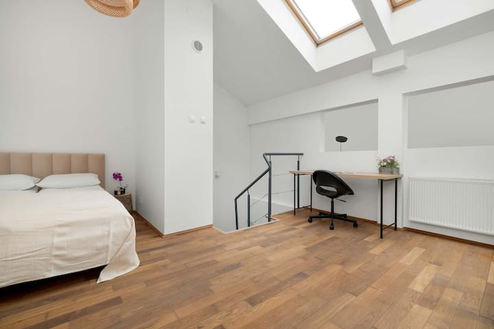 Спалнята има двойно легло в бежово, а до него има бюро със стол, което ще бъде подходящо за дистанционна работа.