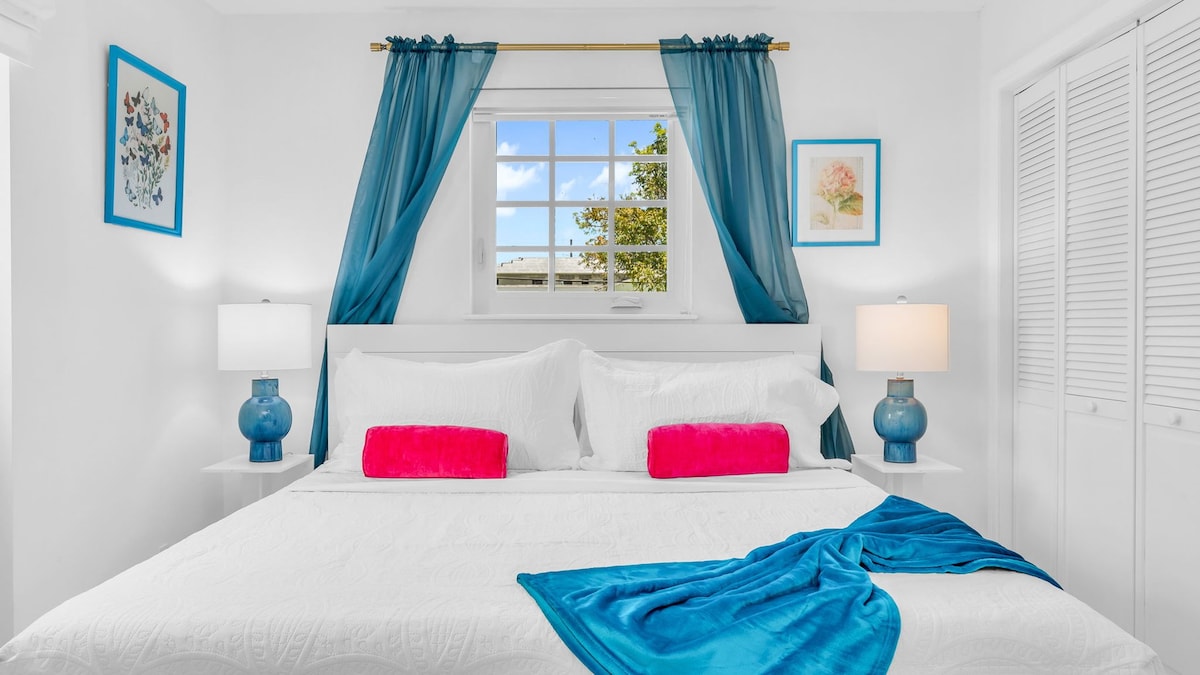 Este vibrante dormitorio principal cuenta con una lujosa cama tamaño king, atrevidos toques de color y acceso directo al patio trasero, perfecto para el café de la mañana o la relajación nocturna. Disfruta de la comodidad de una televisión inteligente, un ventilador de techo y un fácil acceso a la zona compartida