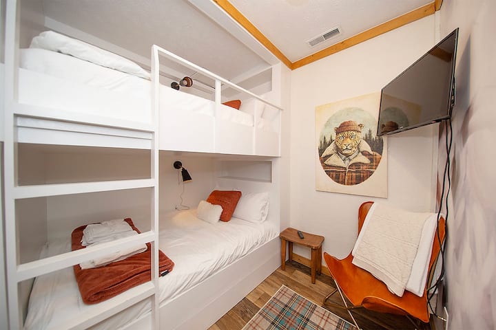 La habitación de la litera de abajo tiene un conjunto de cama completo (¿tal vez queen? Son literas personalizadas, así que no estamos muy seguros. Pero lo que sí sabemos es que son lo suficientemente grandes para 2 personas (siempre y cuando esas personas se caigan bien... o sean pequeñas... o ambas cosas también están bien)