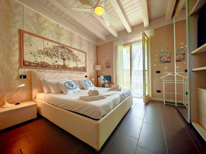 غرفة مزدوجة أنيقة مع عوارض مكشوفة وإمكانية الوصول المباشر إلى الشرفة. تخلق المفروشات الحديثة والاهتمام بالتفاصيل جوًا مريحًا وراقيًا، وهو مثالي للراحة بعد يوم قضاءه على بحيرة غاردا.