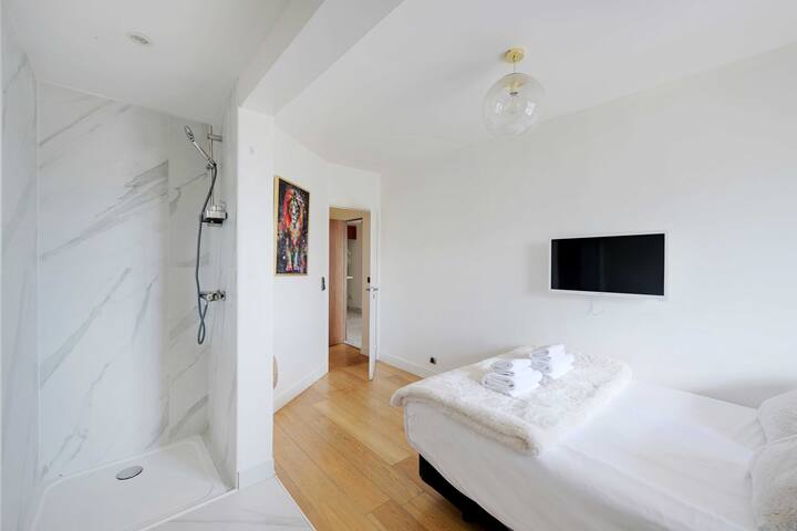 Spavaća soba s bračnim krevetom, TV-om i ormarom.