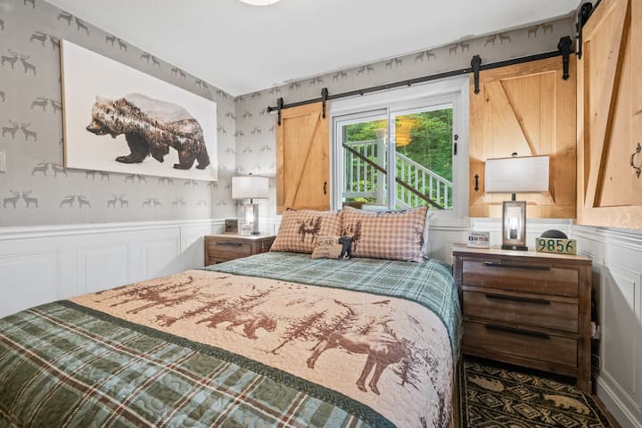 Charming queen bedroom with custom barn-door shutters, Roku TV, spacious closet, and woodland-inspired decor. Peaceful forest views and cozy furnishings make it the perfect mountain retreat.