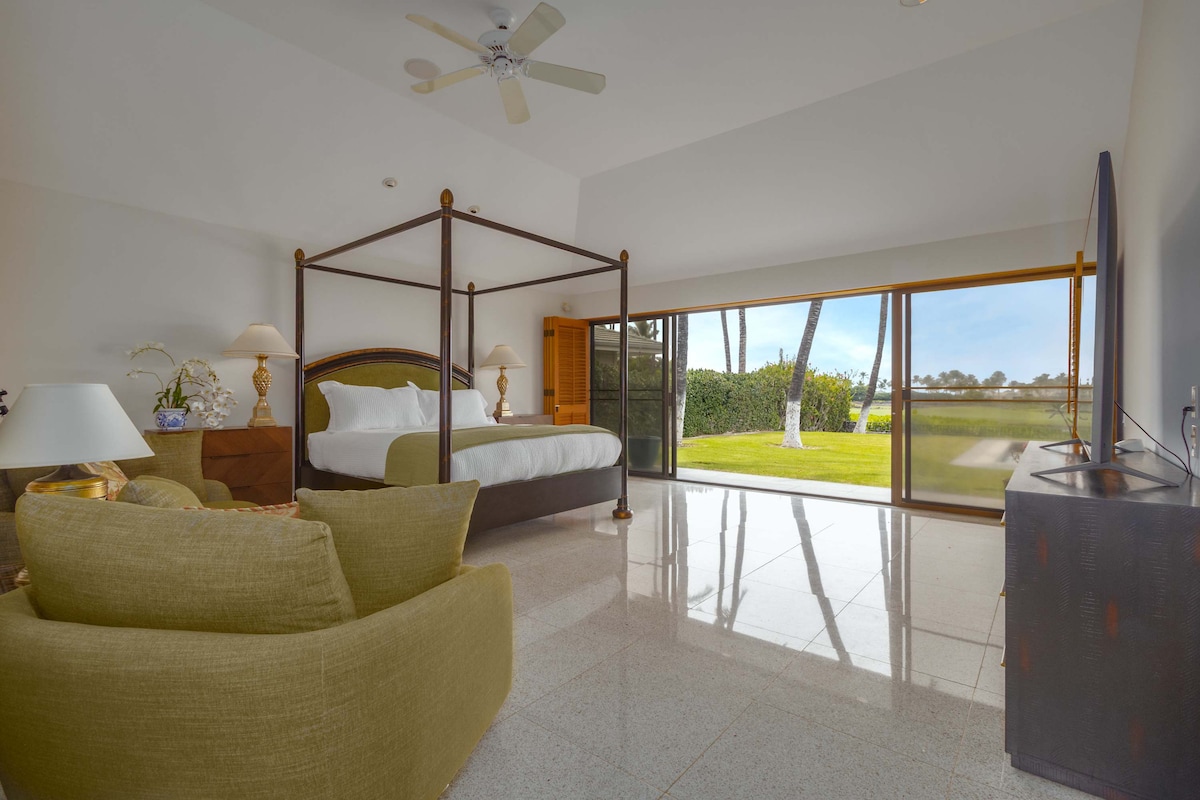 Chambre principale avec lit king size et salle de bain privée, grand dressing et portes coulissantes s'ouvrant sur la terrasse de la piscine et la cour arrière.